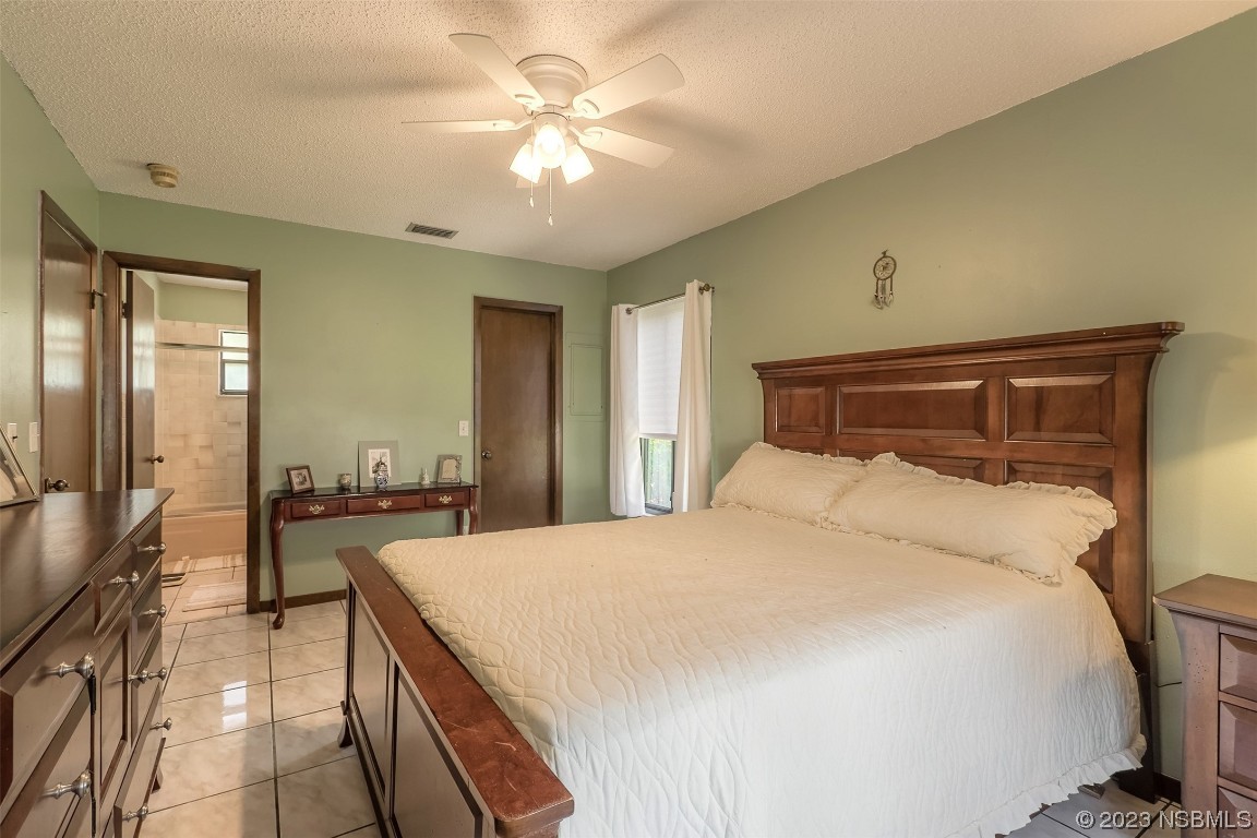 2908 Orange Tree Drive Edgewater, FL 32141 - Photo 5 of 30 a bedroom with a large bed a chandelier and dresser