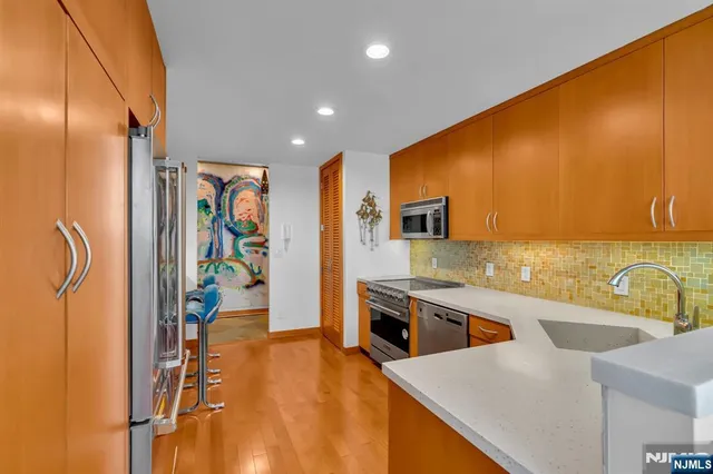 a kitchen with stainless steel appliances granite countertop a sink a stove and a refrigerator