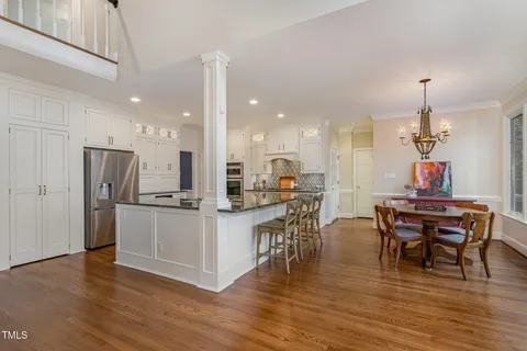 a kitchen with stainless steel appliances kitchen island granite countertop a table chairs and a refrigerator