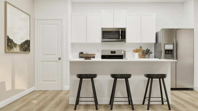 a kitchen with stainless steel appliances white cabinets and wooden floor