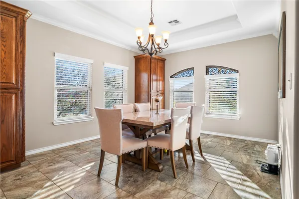 a dining room with wooden floor a chandelier a wooden table and chairs