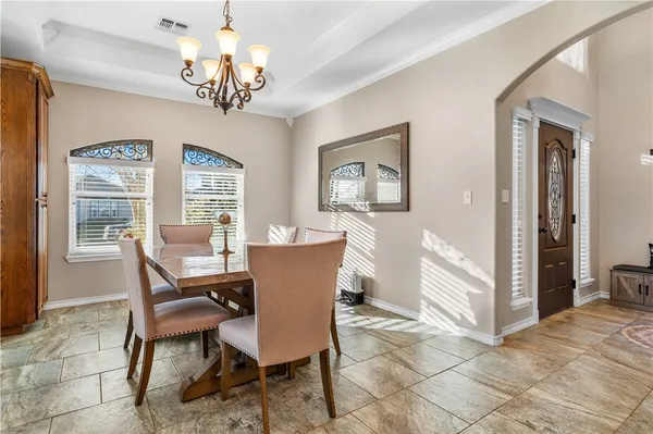 a dining room with wooden floor a chandelier a wooden table and chairs