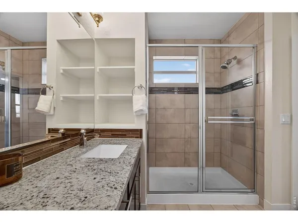 a bathroom with a granite countertop sink a mirror and shower