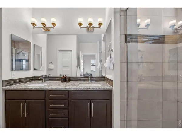 a bathroom with a granite countertop sink a large mirror and a shower
