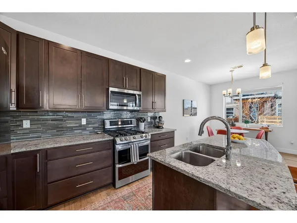 a kitchen with stainless steel appliances granite countertop a sink a stove and cabinets