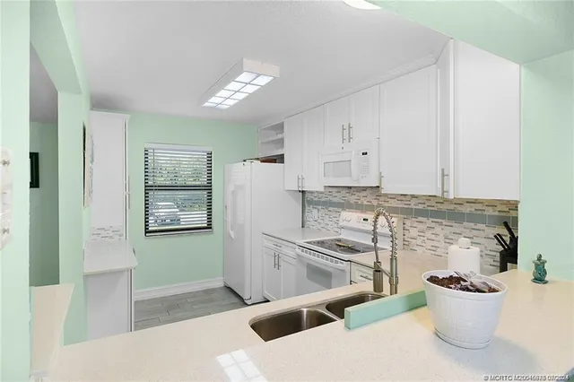 a kitchen with stainless steel appliances kitchen island granite countertop a refrigerator and a sink