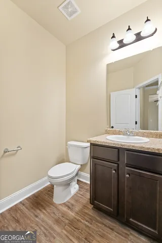 a bathroom with a granite countertop toilet a sink and a mirror