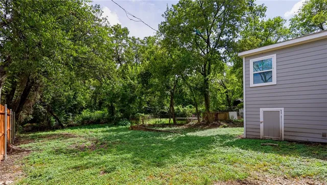 a view of a backyard with plants and large trees