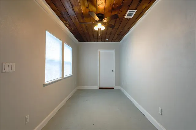 an empty room with chandelier fan and windows