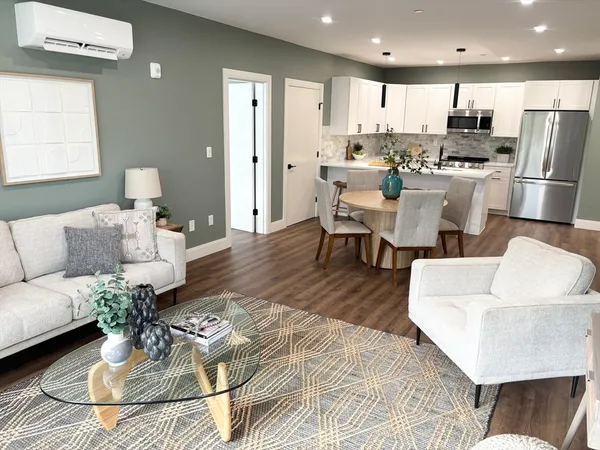 a living room with couches chairs and kitchen view with wooden floor