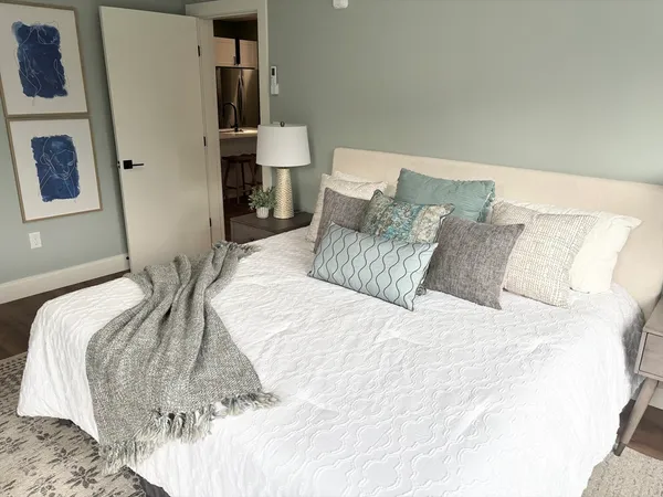 a bed sitting in a bedroom with a white comforter and pillows