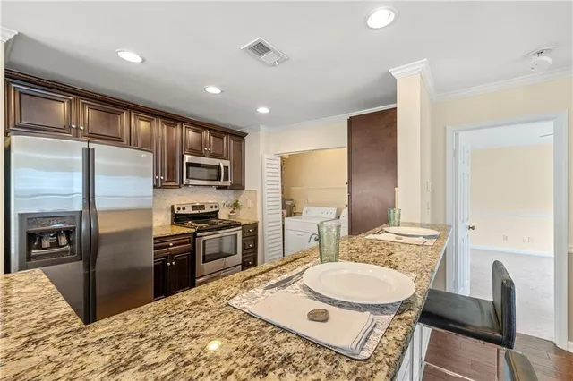 a kitchen with stainless steel appliances granite countertop a sink refrigerator and cabinets