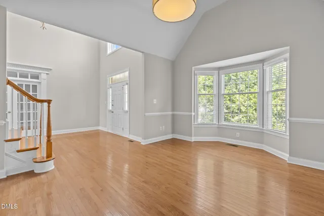 a view of an empty room with wooden floor and a fireplace