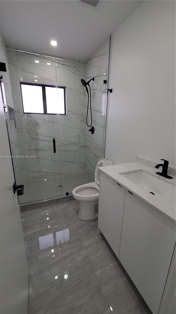 40 Southwest 34th Avenue, Unit A Miami, FL 33135 - Photo 11 of 15 a bathroom with a granite countertop sink a toilet and mirror