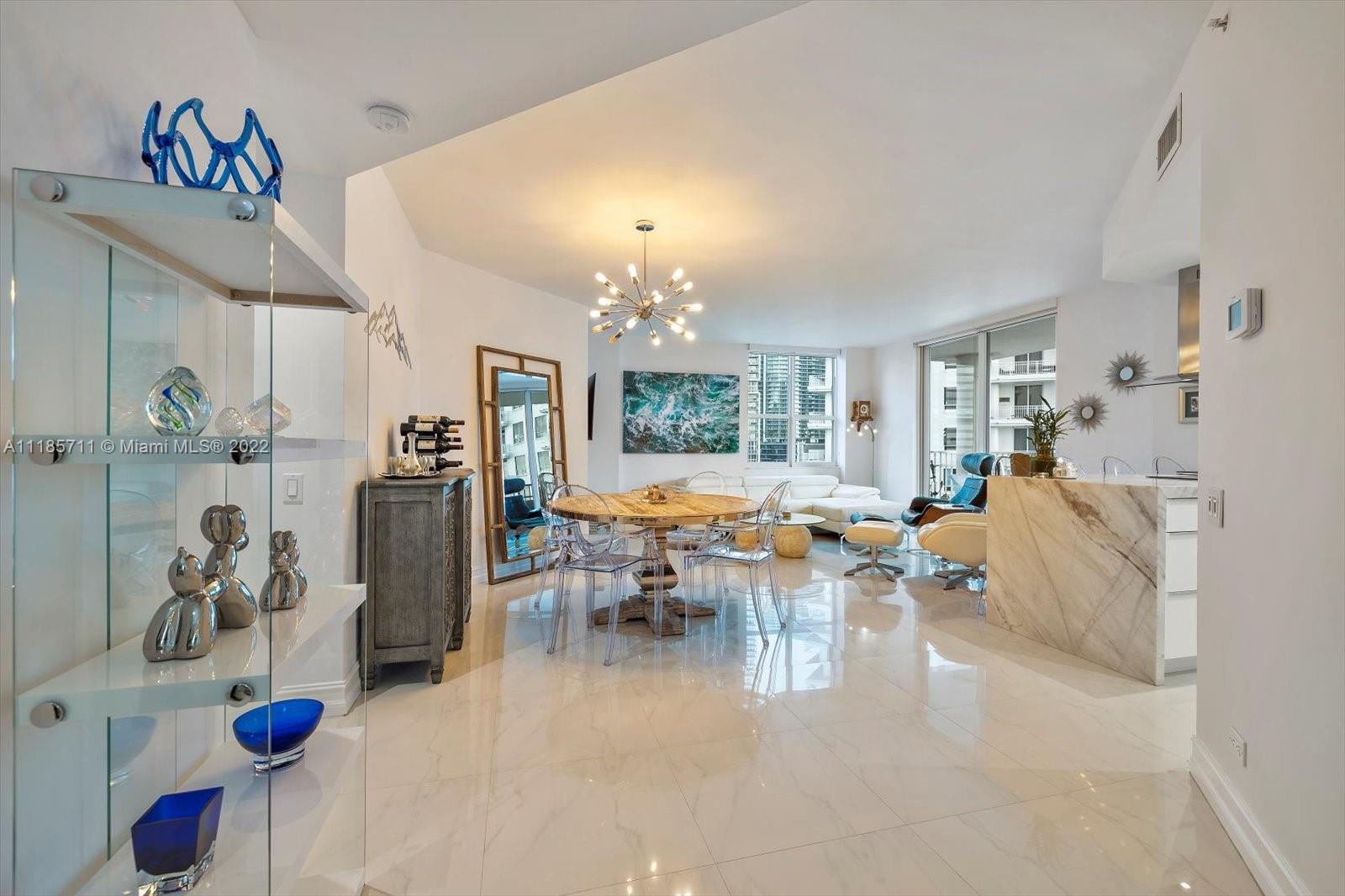 701 Brickell Key Boulevard, Unit 1704 Miami, FL 33131 - Photo 4 of 31 a living room with furniture a chandelier and a large window