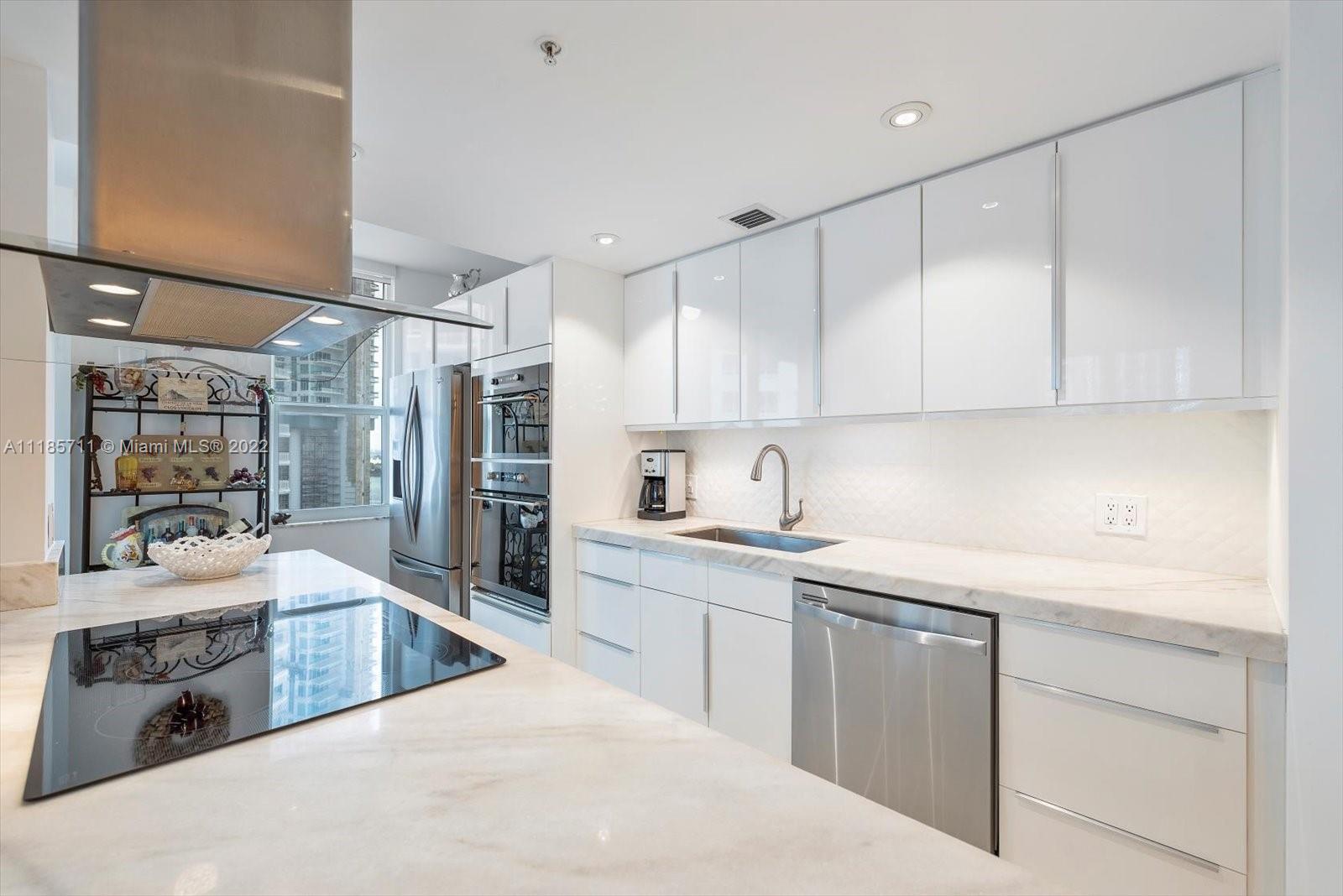 701 Brickell Key Boulevard, Unit 1704 Miami, FL 33131 - Photo 7 of 31 a kitchen with stainless steel appliances kitchen island granite countertop a sink and cabinets