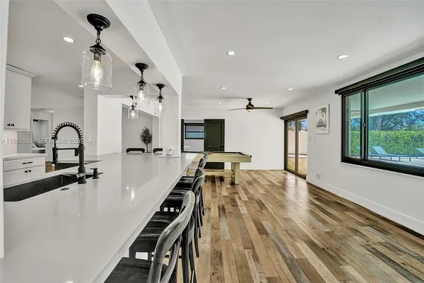 a living room with stainless steel appliances kitchen island granite countertop a sink and wooden floor