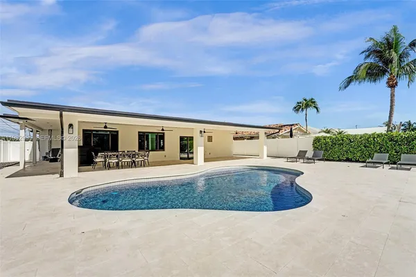 a large white kitchen with stainless steel appliances granite countertop a stove a sink a refrigerator and white cabinets with wooden floor