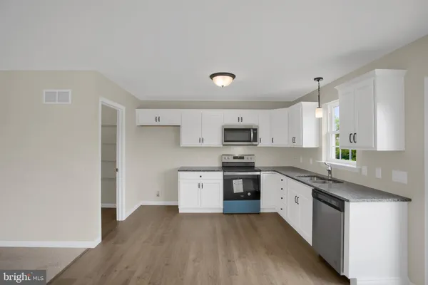 a large kitchen with stainless steel appliances a sink a stove a microwave and cabinets