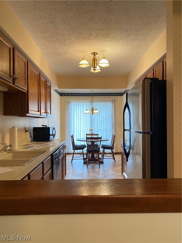 22522 Center Ridge Road, Unit E Rocky River, OH 44116 - Photo 10 of 22 Kitchen with refrigerator, dishwasher, hanging light fixtures, a textured ceiling, and a notable chandelier