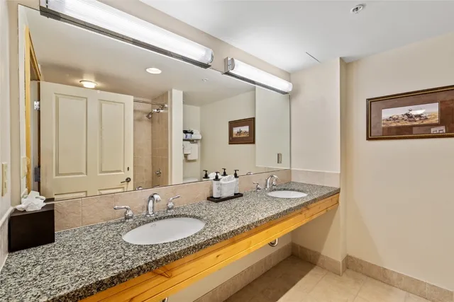 a bathroom with a granite countertop double vanity sink and a mirror