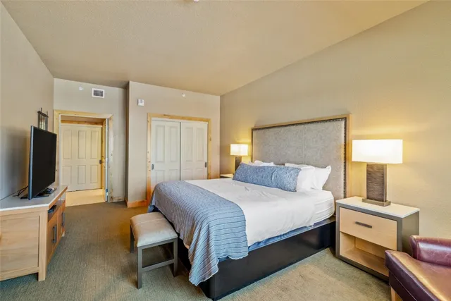 a bedroom with a bed and a flat tv screen on dresser