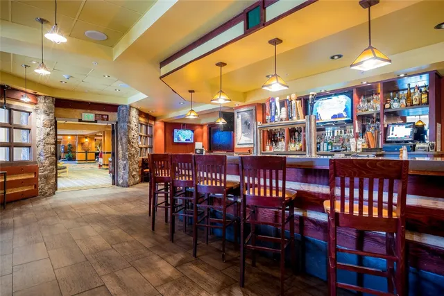 a dining room with stainless steel appliances a dining table chairs and a bookshelf
