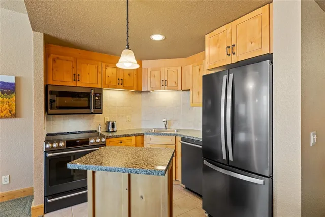 a kitchen with stainless steel appliances granite countertop a refrigerator a stove and a sink with wooden floor