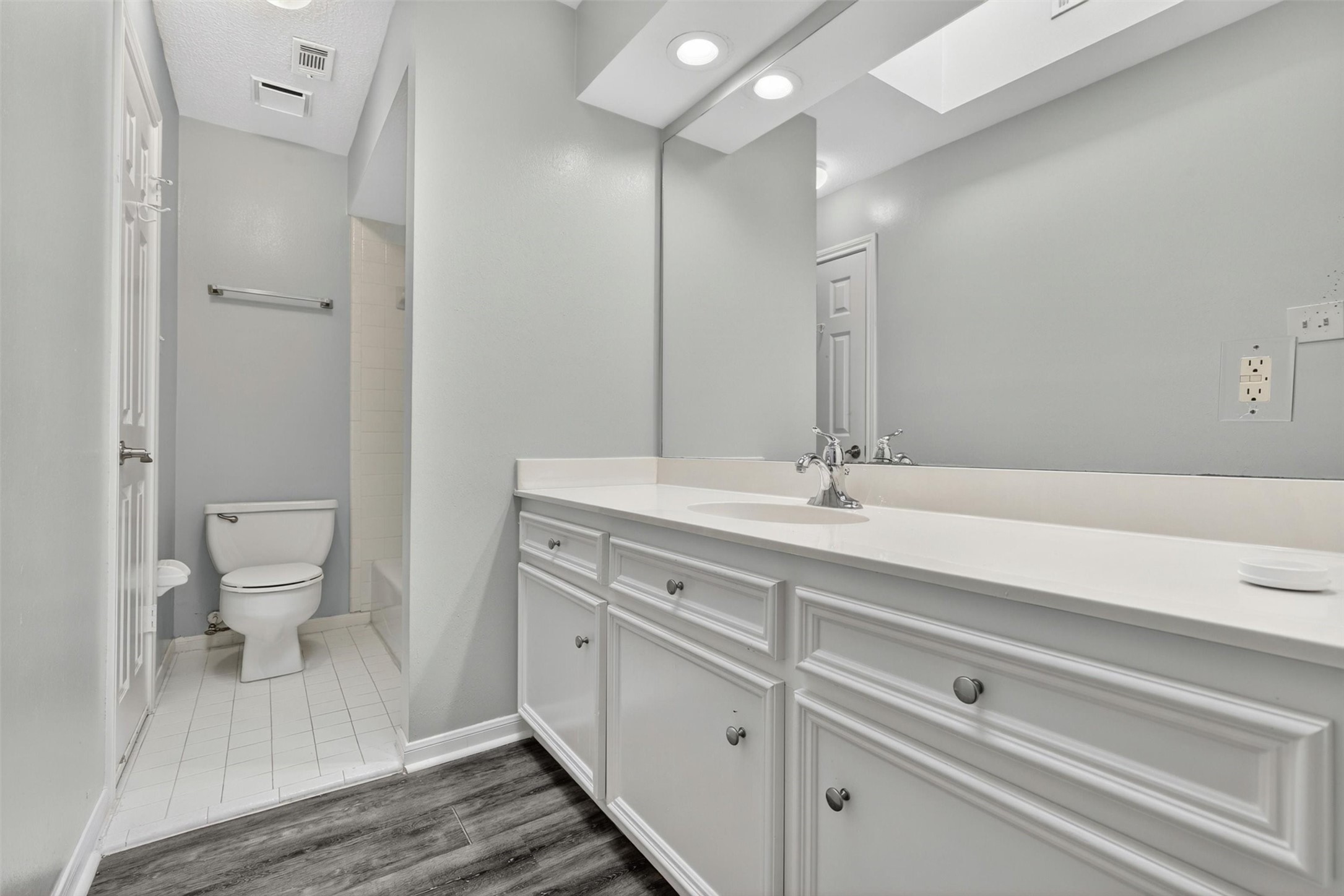 12929 Kingsbridge Lane Houston, TX 77077 - Photo 28 of 42 Bright and spacious second full bathroom featuring an oversized vanity, abundant counter space, and modern finishes that today’s buyers are searching for. The clean neutral color palette, updated flooring, and expansive mirror create a fresh and inviting feel throughout the space. Buyers will appreciate the functional layout, generous storage, and convenient access to the shower and bath area, making it ideal for family, guests, or multi-generational living.