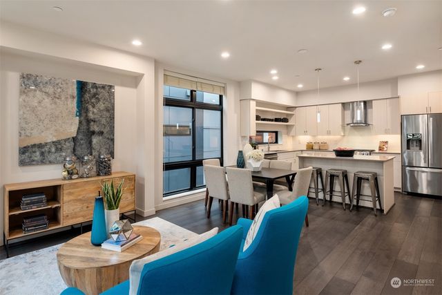 a living room with stainless steel appliances furniture a rug and a kitchen view
