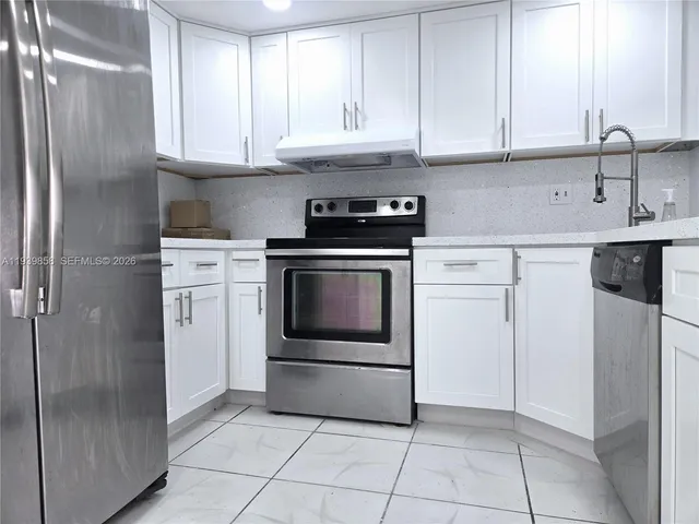 a kitchen with stainless steel appliances granite countertop a stove a refrigerator and a sink