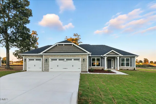 a front view of a house with a garden and trees