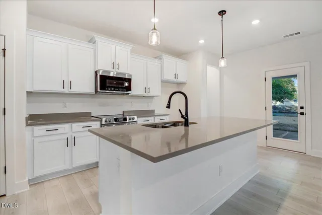 a kitchen with stainless steel appliances granite countertop a sink a stove and a refrigerator