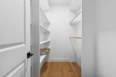 a bedroom with a bed a mirror on dresser and a window