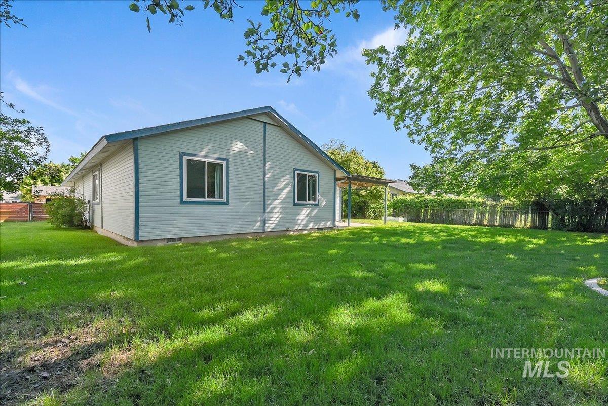 9215 West Preece Street Boise, ID 83704 - Photo 21 of 22 Expansive lawn area featuring a light blue exterior with white trim, a covered patio structure, and a perimeter fence