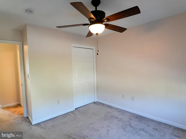 an empty room with a ceiling fan and carpet