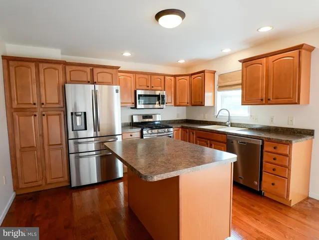 a kitchen with stainless steel appliances granite countertop a refrigerator a stove top oven and a hard wood floor