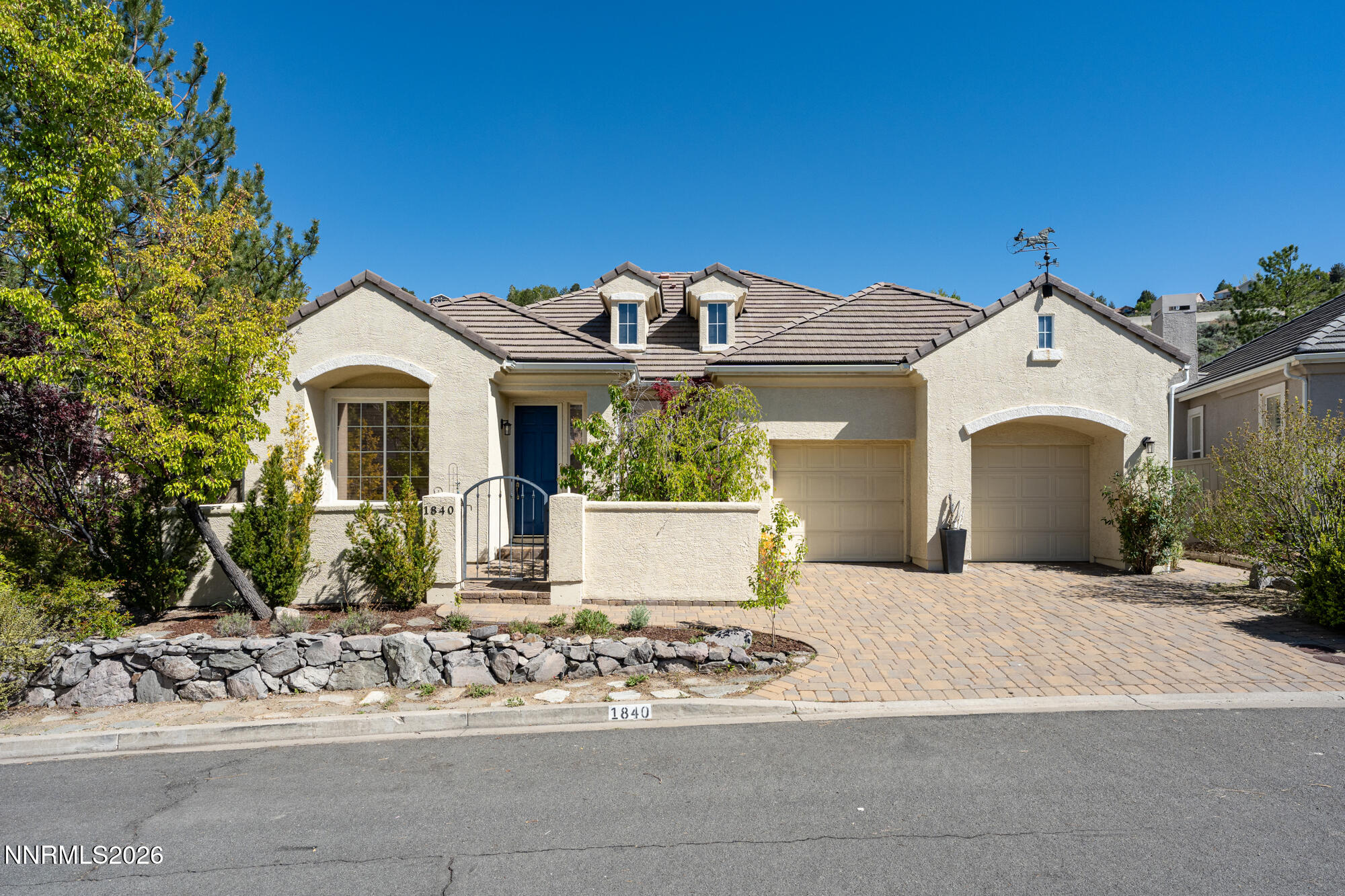 a front view of a house with a garden and a tree