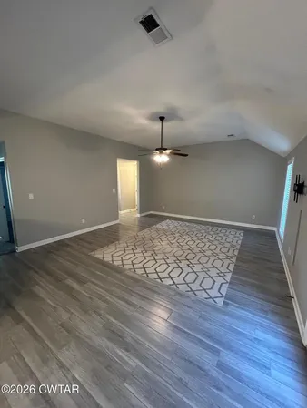 an empty room with wooden floor cabinet and windows
