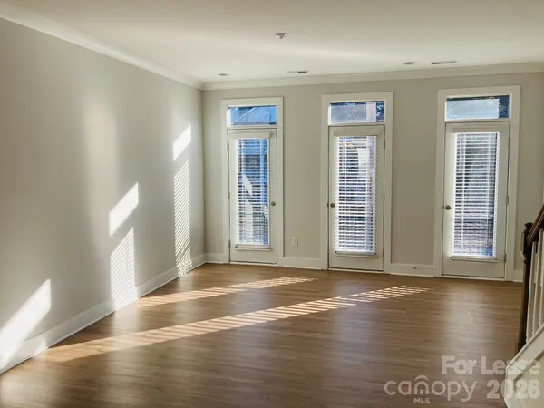 a view of an empty room with window and wooden floor