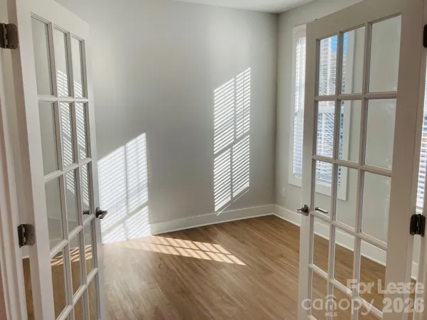 a view of an empty room with a window and wooden floor