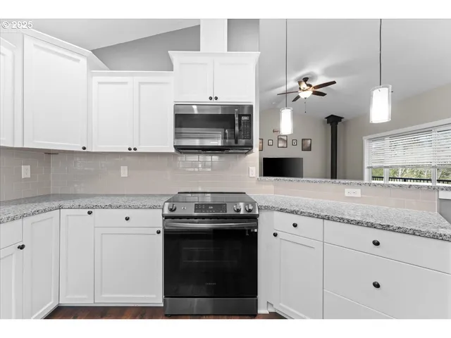 a kitchen with granite countertop a sink stainless steel appliances and white cabinets