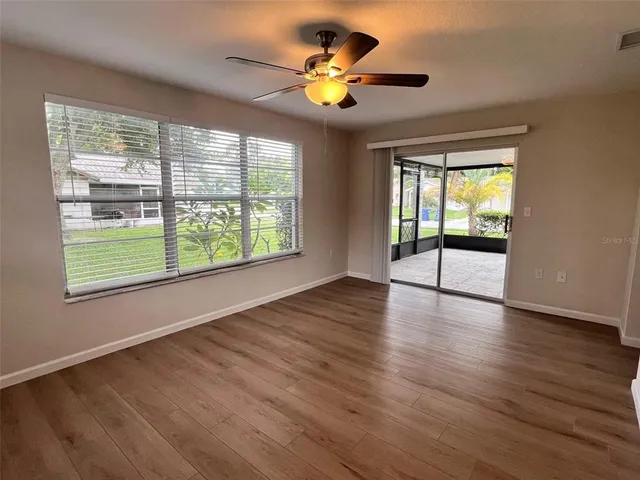 a view of an empty room with window and wooden floor