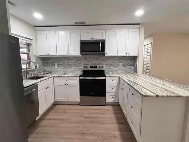 a kitchen with granite countertop white cabinets and stainless steel appliances