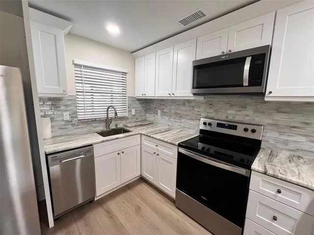 a kitchen with white cabinets and black appliances