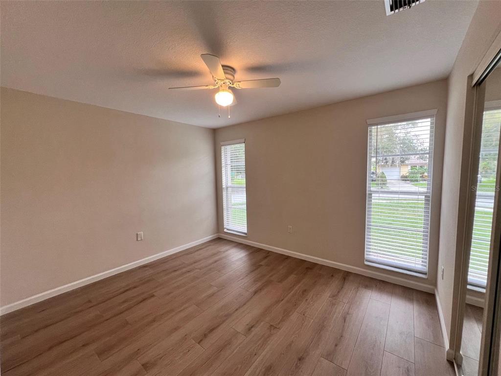 7020 Wentworth Way New Port Richey, FL 34655 - Photo 9 of 22 an empty room with wooden floor fan and windows