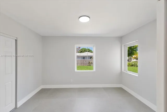 an empty room with windows and mirror