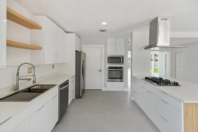 a kitchen with stainless steel appliances kitchen island a stove a sink and a refrigerator