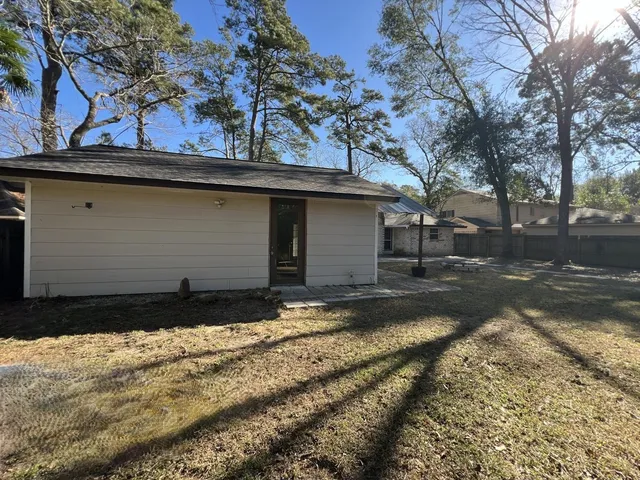 a backyard of a house with large trees and outdoor seating