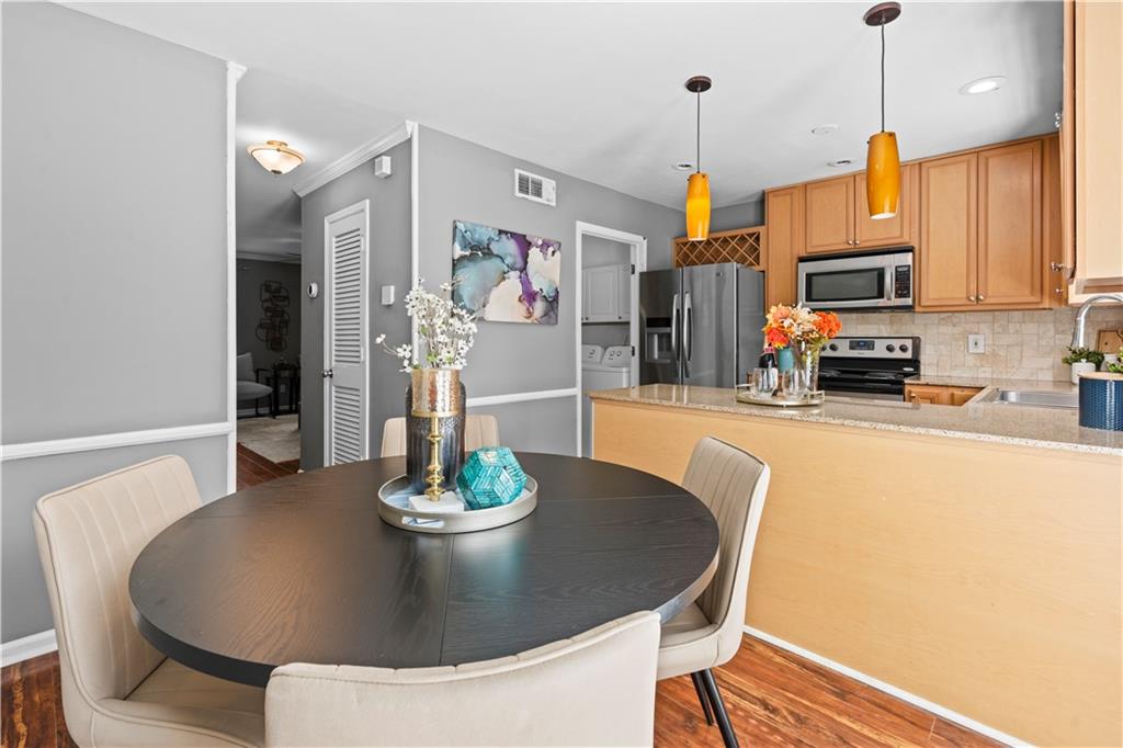 1101 Collier Road Northwest, Unit D5 Atlanta, GA 30318 - Photo 7 of 38 a kitchen with stainless steel appliances granite countertop a dining table chairs and a refrigerator